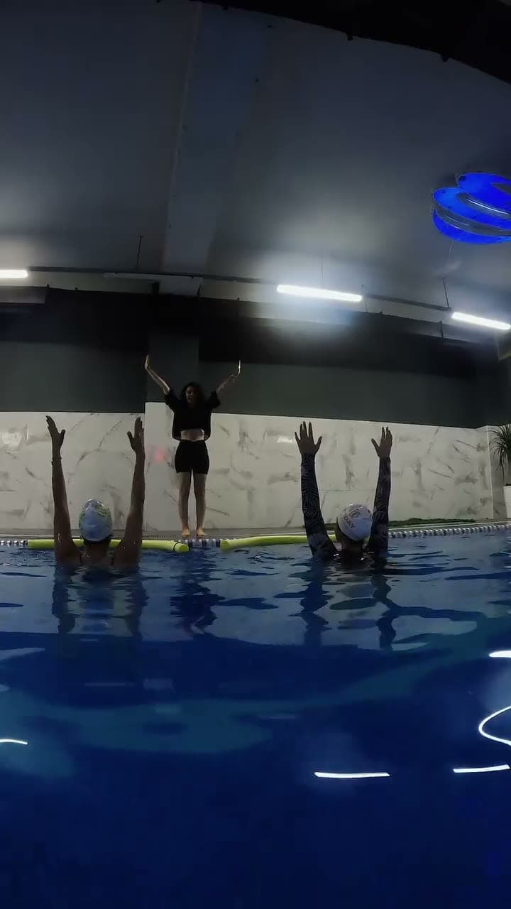 Kapalı havuzda kollarını kaldırmış su yogası grubu