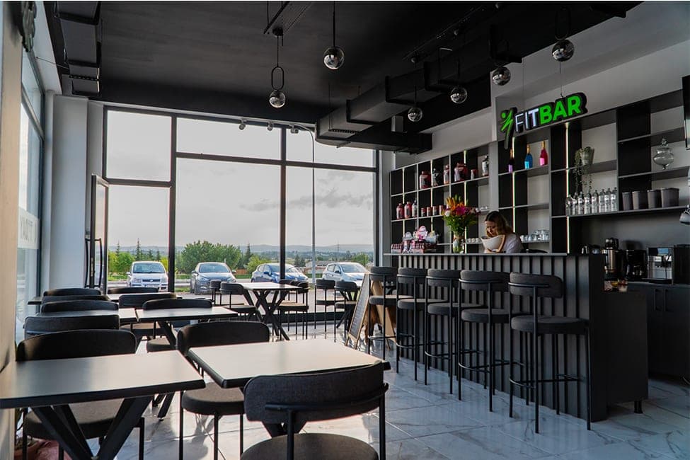 Today Living Club içindeki FitBar: bar tezgahı, yüksek tabureler, masalar ve manzaralı geniş pencereler