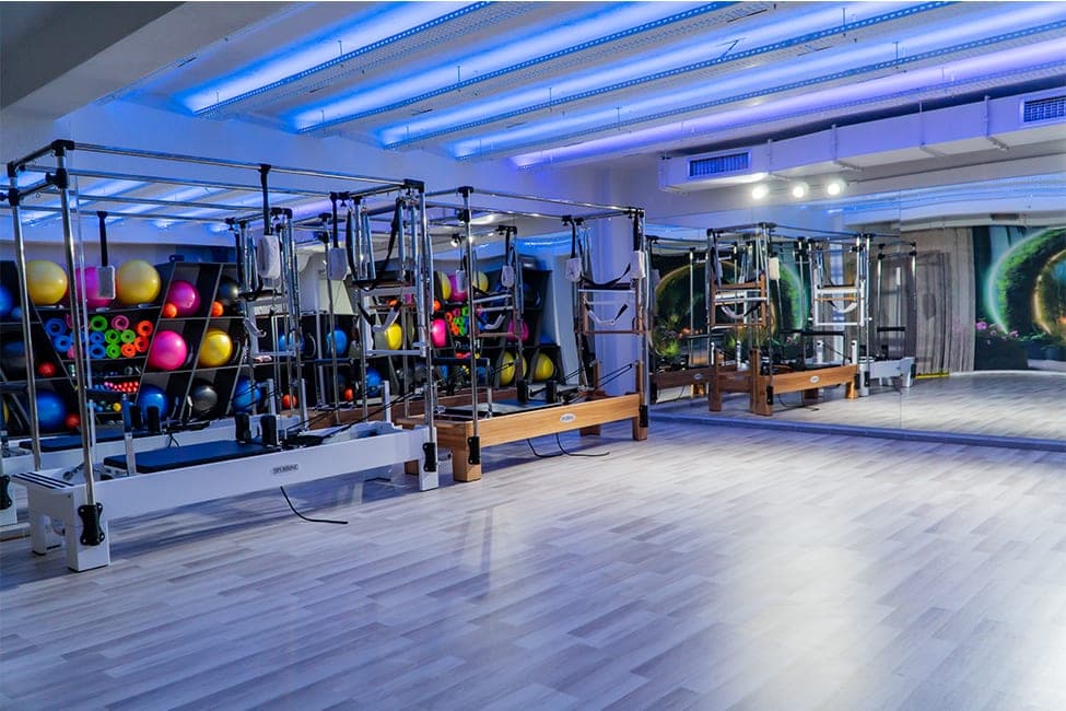 Today Living Club pilates stüdyosu: reformer aletleri, renkli pilates topları ve matlar için raf duvarı, ayna ve mavi LED tavan aydınlatması