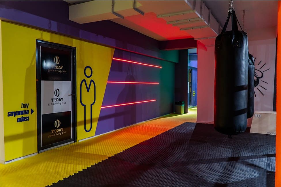 Today gym & living club logolu bay soyunma odası kapısı, sarı duvar ve kırmızı neon ışık şeritleriyle boks alanı koridoru