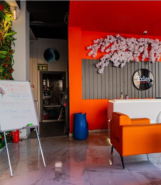 Today Living Club resepsiyonu: turuncu duvarlar, beyaz karşılama bankosu, Today logosu ve turuncu deri koltuklar