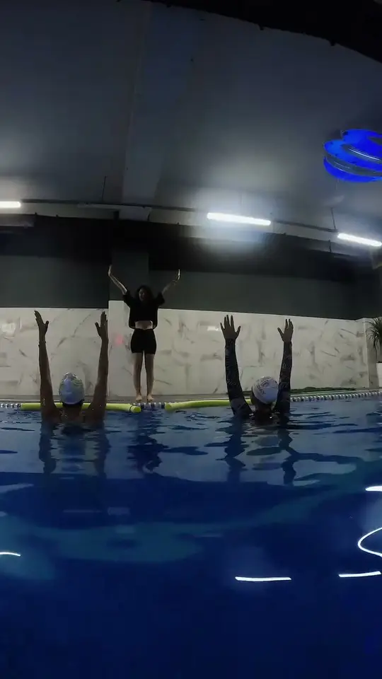 Kapalı havuzda kollarını kaldırmış su yogası grubu